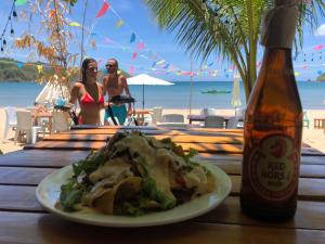 爱妮岛Zhaya's Beach & Cottages的一瓶啤酒旁边的桌子上放着一盘食物