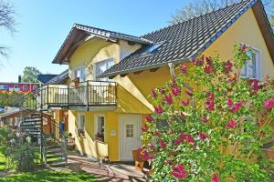 巴贝Ferienwohnungen Familie Dinda的黄色房子,设有阳台和鲜花