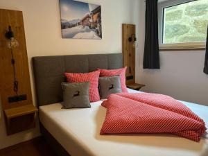 乌姆豪森Alp Apart Niederthai的一间卧室配有红色和白色枕头的床