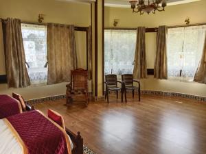 耶拉吉里Hillfort Hotels & Resorts Yelagiri的一间卧室配有一张床、椅子和窗户。