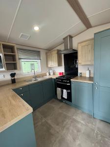 达农The Roecliffe Sea View 9的厨房配有蓝色橱柜和炉灶烤箱。