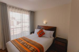 库斯科Quechua ApartHotel的一间卧室设有一张大床和窗户