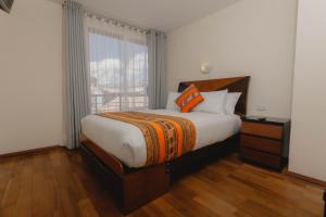 库斯科Quechua ApartHotel的一间卧室设有一张大床和一个窗户。