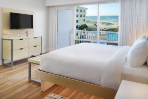 彭萨科拉海滩万豪彭萨科拉海滩春季山丘套房酒店的一间卧室配有一张床、一台电视和一个阳台
