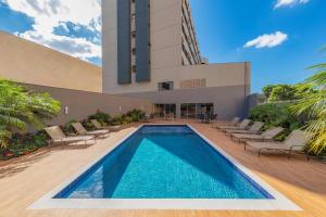 隆德里纳Hotel Thomasi Express - Londrina的一座带椅子的游泳池以及一座建筑