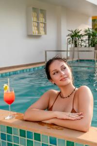 帕纳吉Bloom Hotel - Dona Paula的游泳池里的女人喝一杯