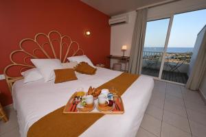 阿格德角Hôtel Bellevue Cap d'Agde的一间酒店客房,配有一张带食物盘的床