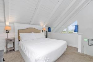 洋滨市Tidal House 9的卧室配有白色的床和窗户。