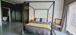 CarolinaRand Self-catering Accommodation的一间卧室配有一张天蓬床和一把椅子