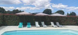 弗维沃L'Ansolanette - Chambre d'hôtes的一组椅子和遮阳伞,位于游泳池旁