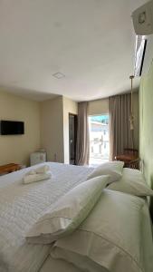 伊塔卡雷Humaita Pousada的卧室配有带枕头的大床和窗户。