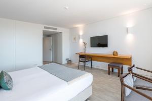 托朗维尔多盖奥酒店的一间卧室配有一张床和一张书桌及电视