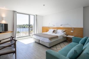托朗维尔多盖奥酒店的一间卧室配有一张床、一张沙发和一台电视。