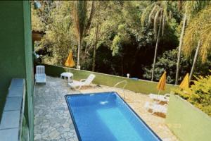 迈里波朗Chácara Paraíso的庭院内的游泳池,配有椅子和遮阳伞