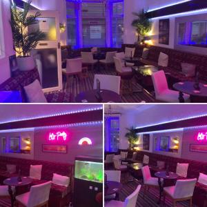 布莱克浦Bromptons的餐厅设有紫色灯和桌子以及电视