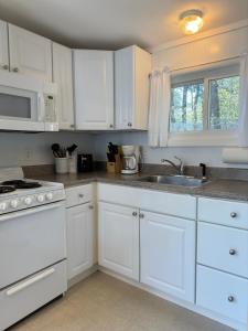 韦尔弗利特The Even'tide的白色的厨房配有白色橱柜和水槽