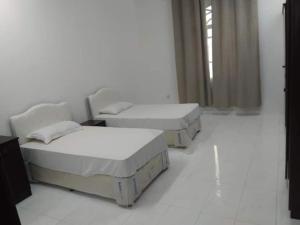 塞拉莱Ganaen Salalah的白色客房的三张床,设有窗户