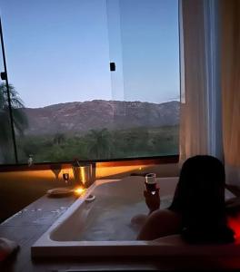 西波山Pousada Belvedere da Serra的坐在浴缸里喝一杯葡萄酒的人