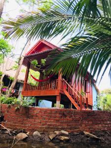 贡布Retro Kampot Guesthouse的砖墙顶部有甲板的房子