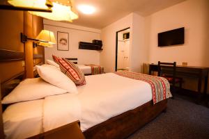 库斯科Hotel Raymi的酒店客房配有带白色床单和枕头的床。