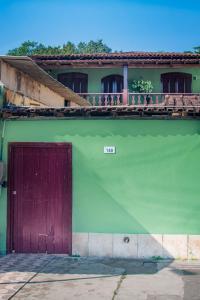 帕拉蒂Casa Surya Paraty的绿色建筑,设有红色的门和阳台