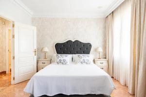 塞维利亚Puerta de Jerez II的一间卧室配有一张白色大床和黑色床头板