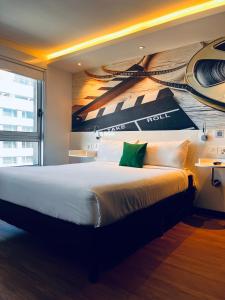 蒙得维的亚ibis Styles Montevideo Biarritz的卧室配有一张大床,墙上挂有绘画作品