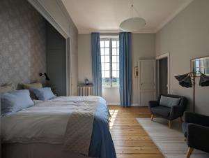 OudonChâteau Haute Roche的一间卧室配有一张大床和一把椅子