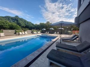 门多萨拉宜斯艾克卡吉酒店的一个带椅子和遮阳伞的游泳池