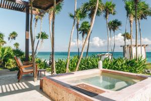 图卢姆Mi Amor Boutique Hotel-Adults Only的棕榈树海滩旁的浴缸