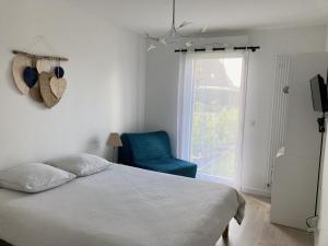 卡纳克TY DOLMEN DU Plages à pied 2 vélos WIFI的一间卧室配有一张床、一把蓝椅和一个窗户。