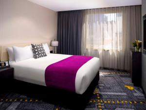 墨尔本Pullman Melbourne City Centre的一间设有大床和窗户的酒店客房