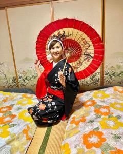 八户市青森伝統芸能を楽しめる繭子の宿的坐在床上拿着红伞的女人