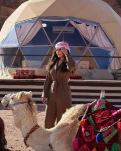 瓦迪拉姆Desert relax camp的站在帐篷前骆驼旁的女人