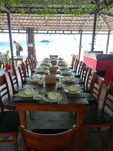瓜隆岛SCARLET SAILS BUNGALOW的一张长木桌子,上面有椅子和盘子