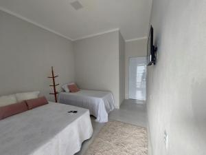 皮拉尼亚斯Pousada Luz do Sol的白色的客房配有两张床和电视。