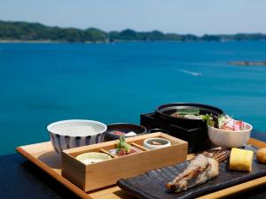 那智胜浦町KAMENOI HOTEL Nachi Katsuura的桌上食物的托盘,享有水景