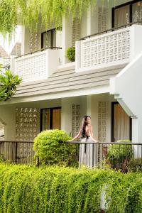 会安The Saga Hotel Hoi An的站在建筑物前阳台的女人