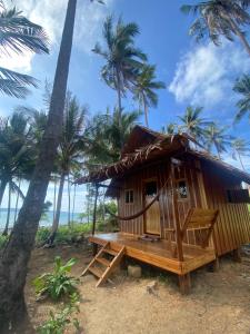 瓜隆岛Lily's Beach Bungalows的棕榈树海滩上的一个小棚屋