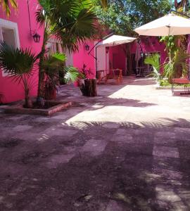 科苏梅尔Casa Isabella的一座粉红色的建筑,在庭院里配有桌子和遮阳伞