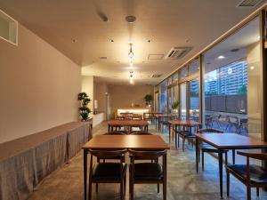 泉佐野EZ HOTEL 関西空港 Seaside的餐厅设有木桌、椅子和窗户。