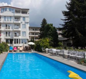 奥赫里德乔丹别墅酒店的一座大型蓝色游泳池,位于大楼旁边