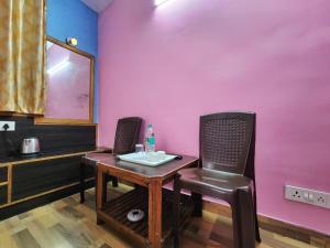 西姆拉Hotel Tirupati Regency Near Mall Road的粉红色墙壁的房间里一张桌子和椅子