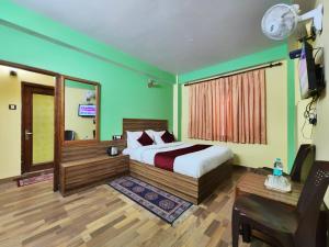 西姆拉Hotel Tirupati Regency Anandam的一间卧室配有一张床、一张书桌和一台电视