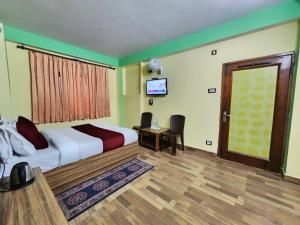 西姆拉Hotel Tirupati Regency Near Mall Road的卧室配有床、电视和门