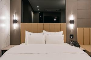 安东市Brown Dot Hotel Andong Ok-dong的卧室配有带白色枕头的大床