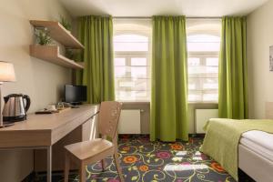 维尔纽斯兰宁凯城市酒店的酒店客房配有书桌和绿色窗帘