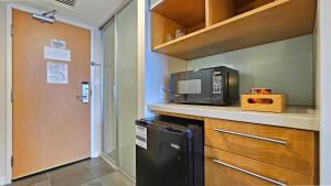 檀香山Ocean View Room at a resort的厨房配有微波炉和黑冰箱。