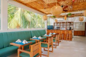 帕杰Samawa Living的餐厅设有绿色的沙发和木桌及椅子
