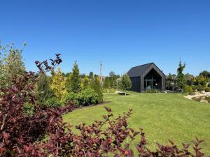 TīnūžiBlack House- Lake garden sauna的一座大型草地庭院,有一座黑色的建筑